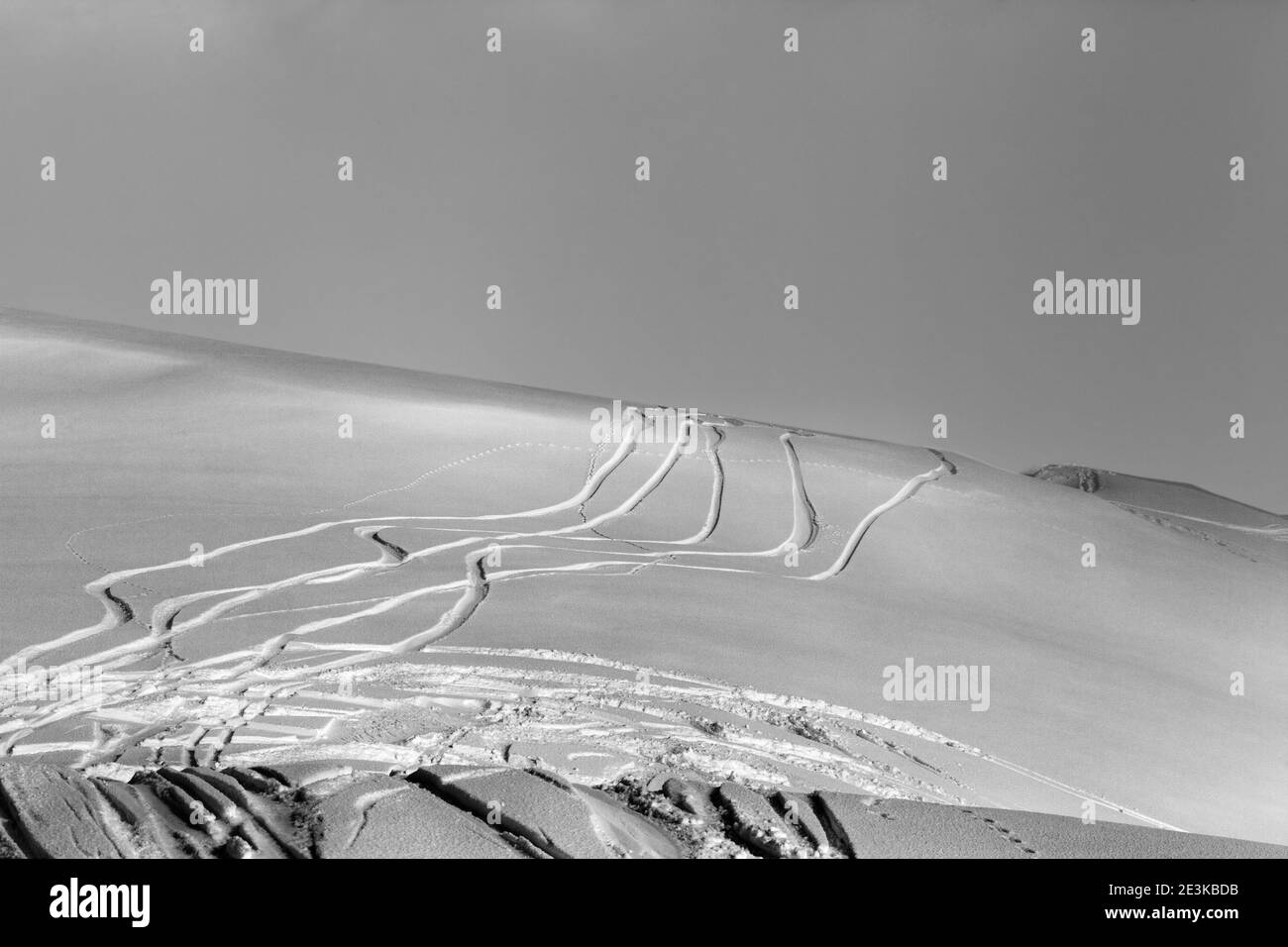 Snowy off-piste ski slope with trace from skis and snowboards at winter night. Black and white toned landscape. Stock Photo