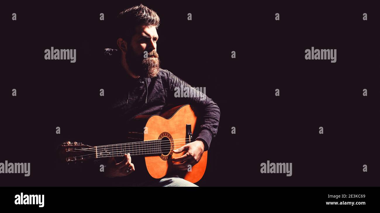Bearded man playing guitar, holding an acoustic guitar in his hands. Music concept. Bearded guitarist plays. Play the guitar. Beard hipster man. Copy Stock Photo