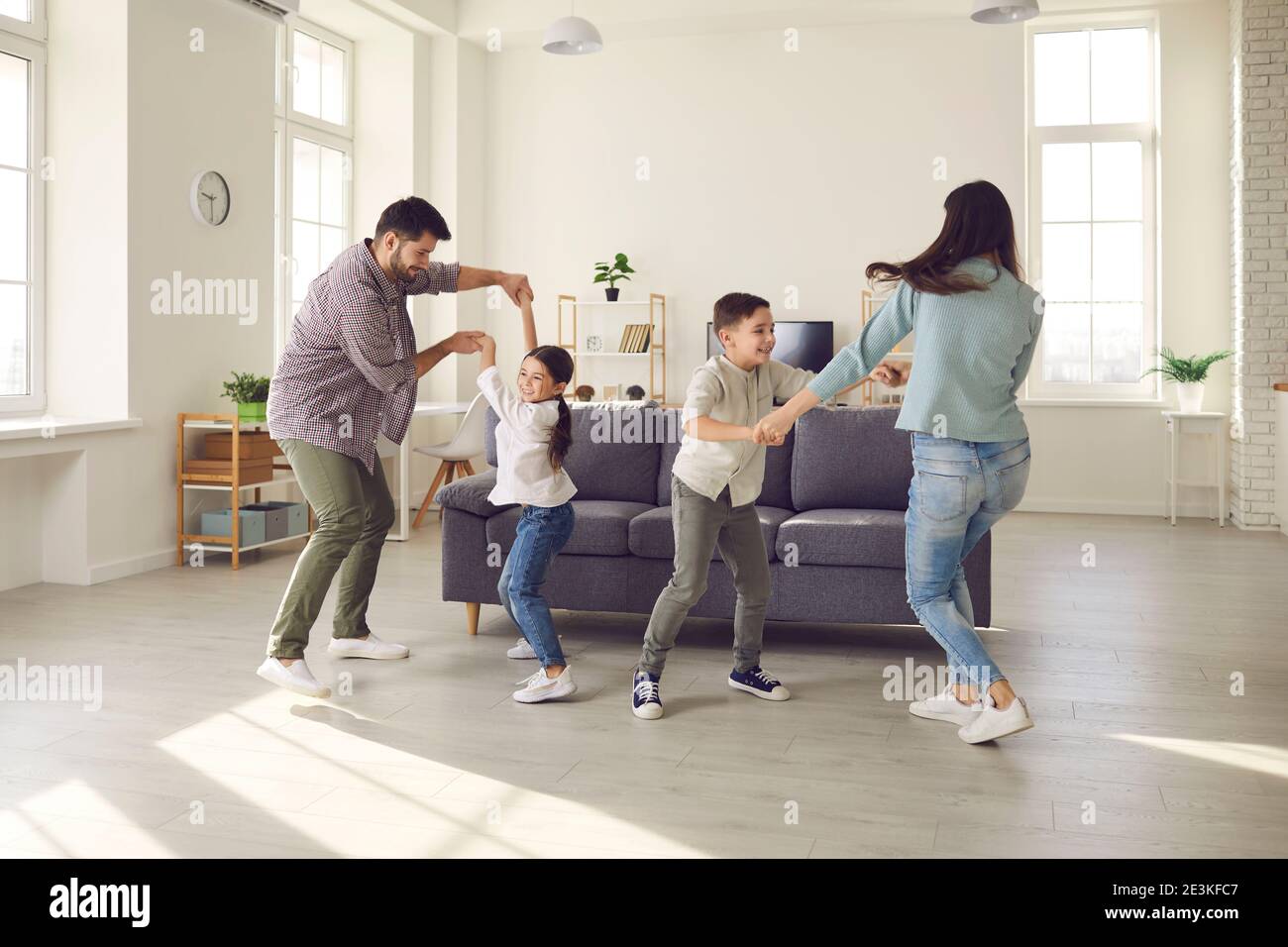 Happy parents and children dancing and having fun in the living-room of new apartment Stock Photo