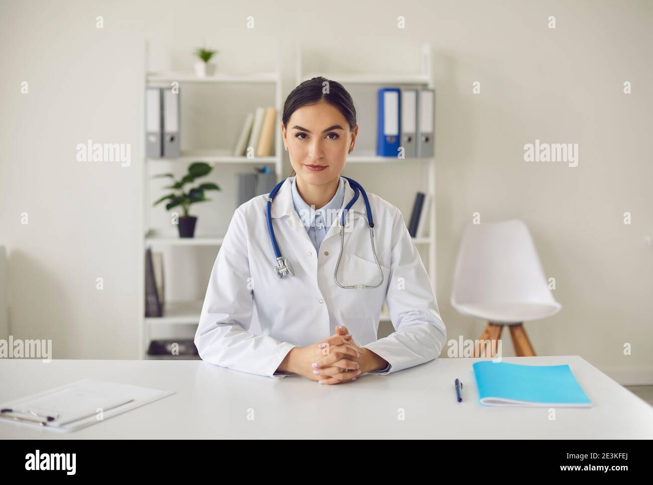 Young general practitioner looking at camera while sitting at table in her office Stock Photo