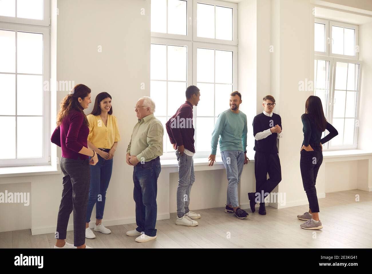 Office workers stand in a bright hall and communicate with each other during a break from work. Stock Photo