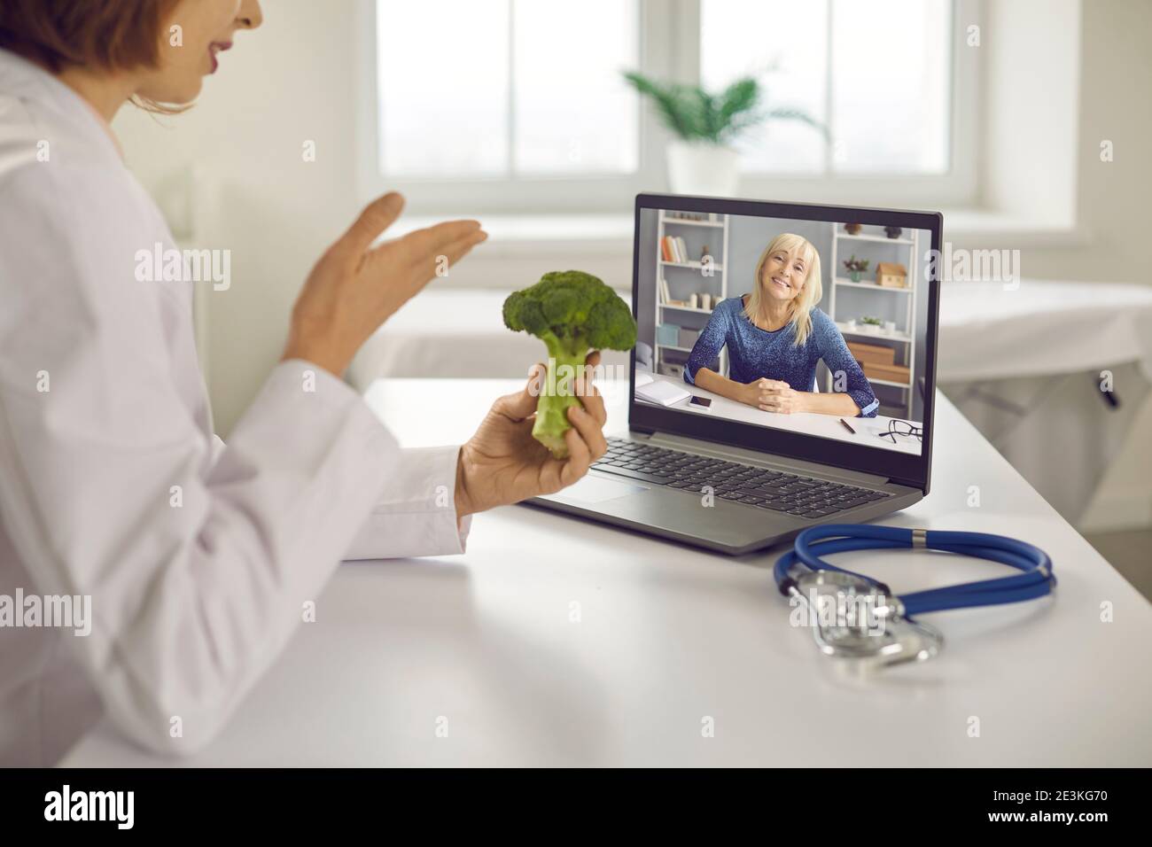 Doctor video calling senior patient on laptop and giving her healthy diet advice Stock Photo