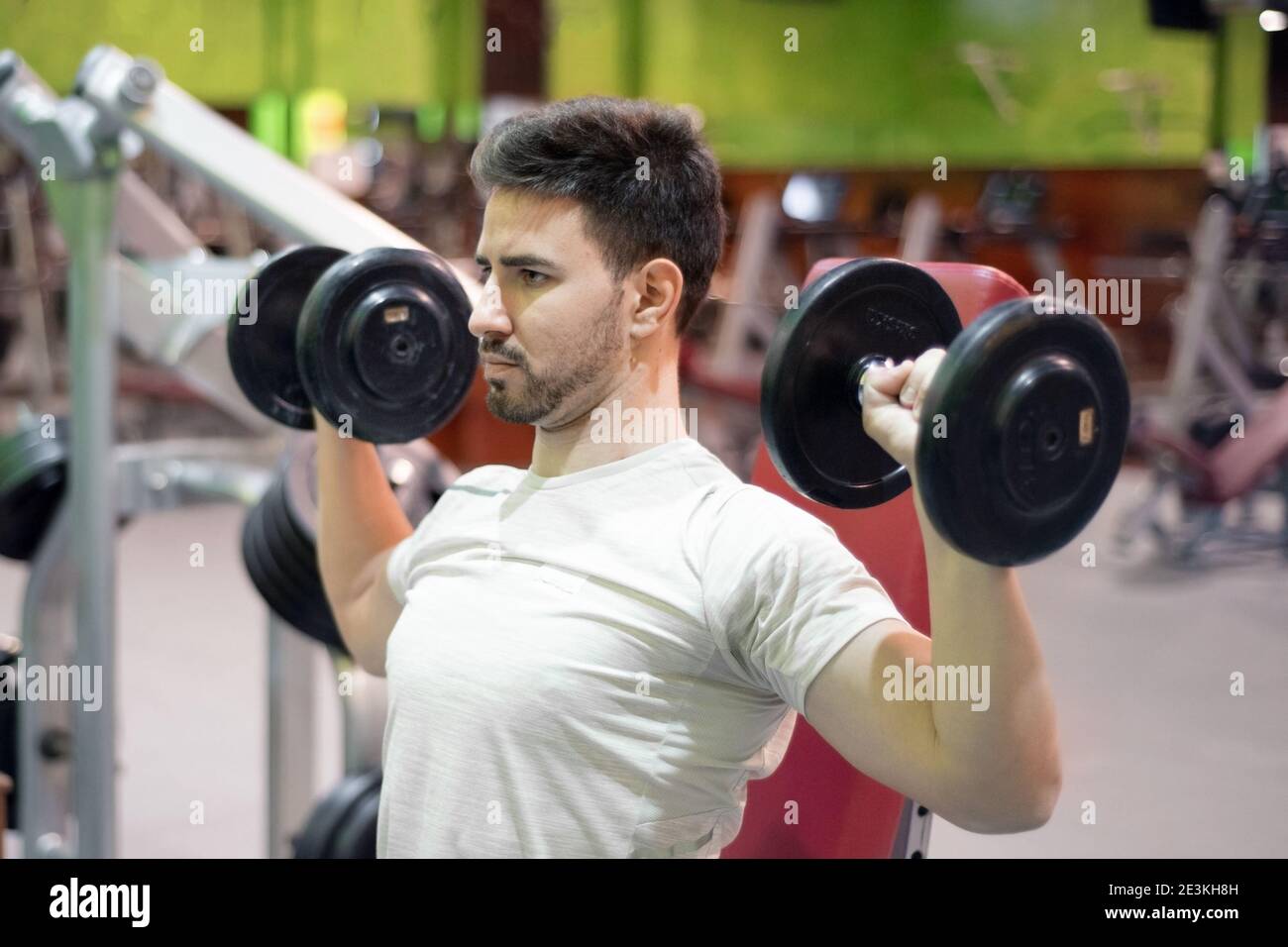 Gym man strength training lifting weights. High quality photo Stock