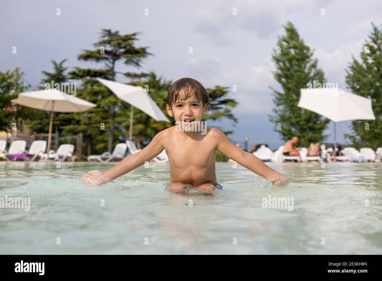 Cute little boy kid child splashing in swimming pool having fun leisure