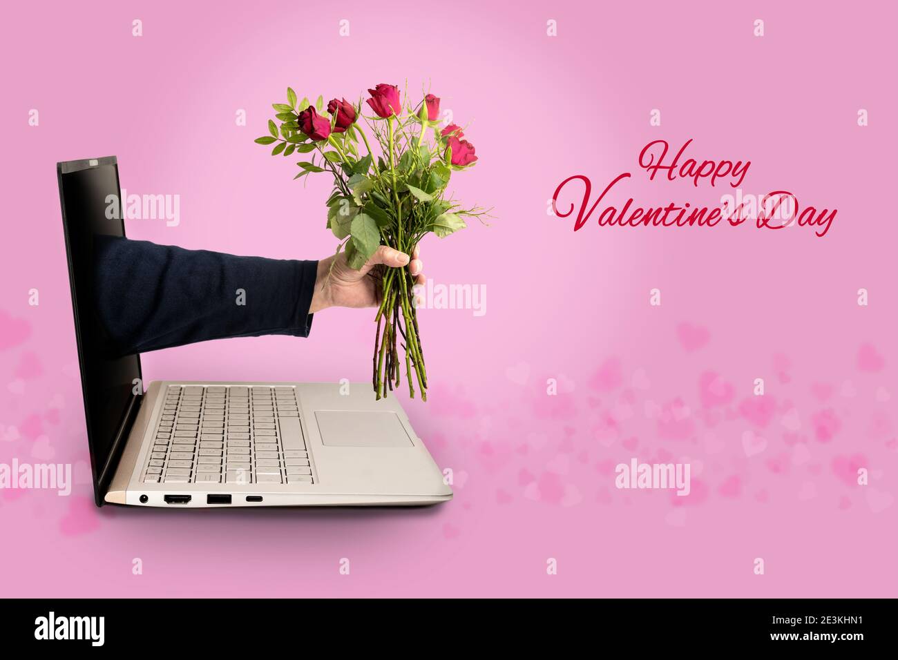 Hand of a man with a bouquet of roses coming out of a laptop screen, text Happy Valentines Day, love concept with social distance during covid-19 pand Stock Photo