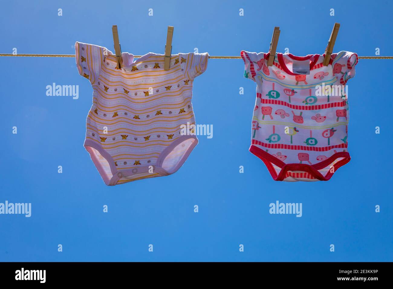 Freshly laundered baby clothes hanging outdoors in the fresh air. Stock Photo