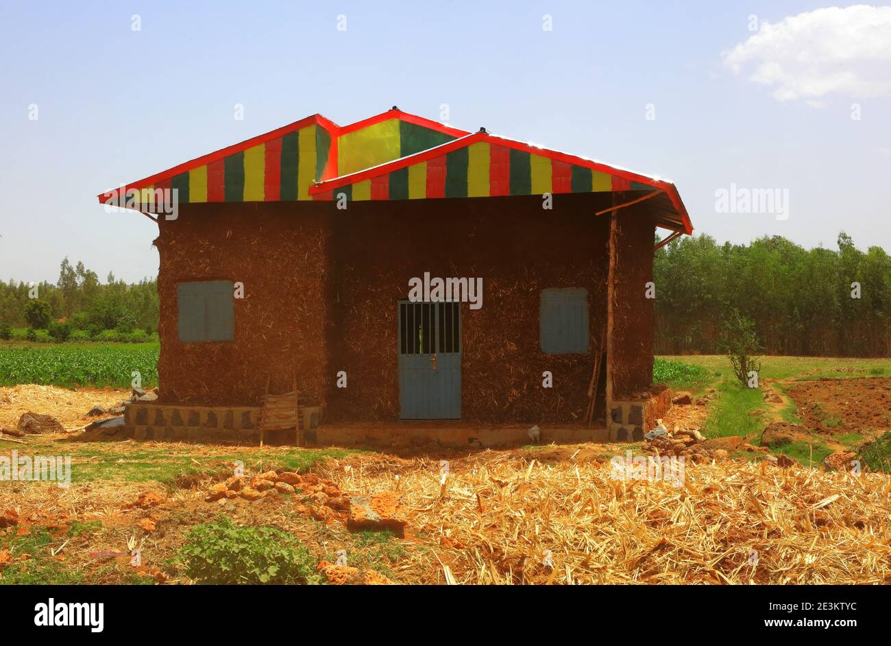 A modest mud and straw house featuring a multicoloured roof painted in