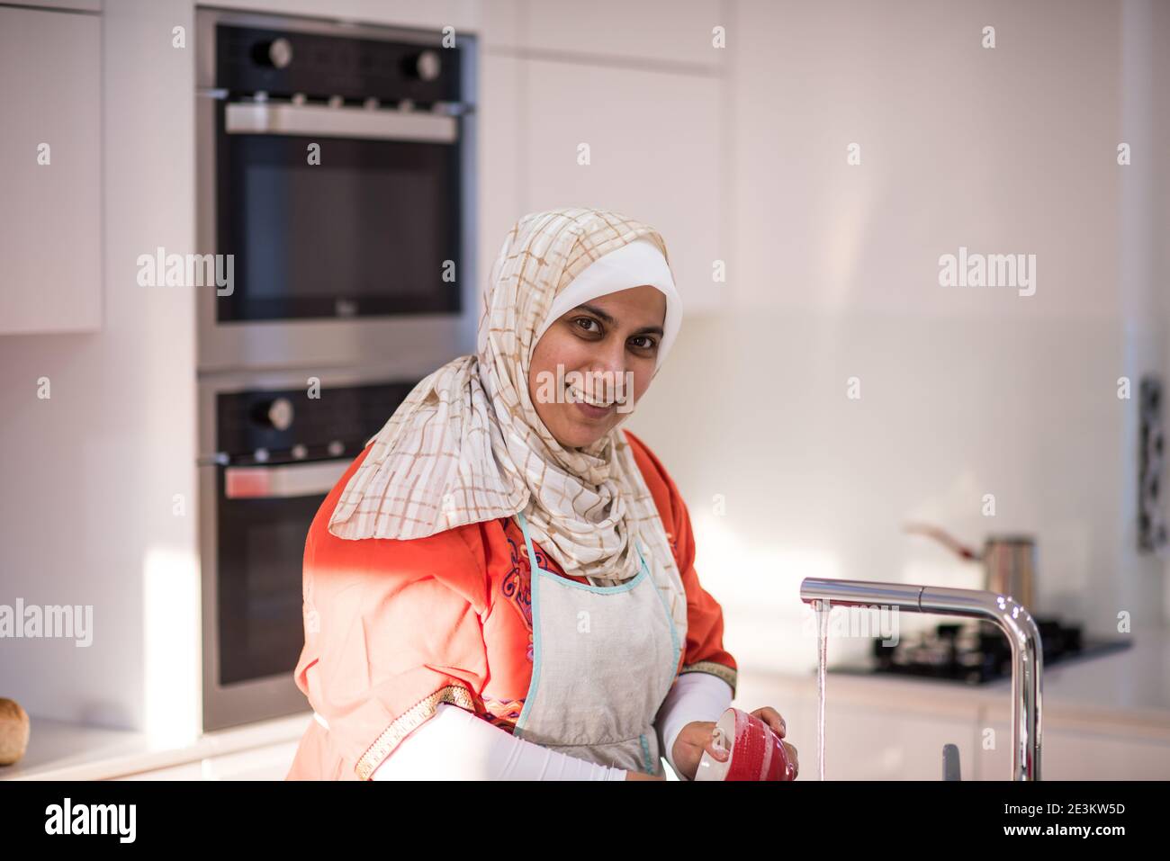 Muslim traditional woman cleaning in kitchen Stock Photo