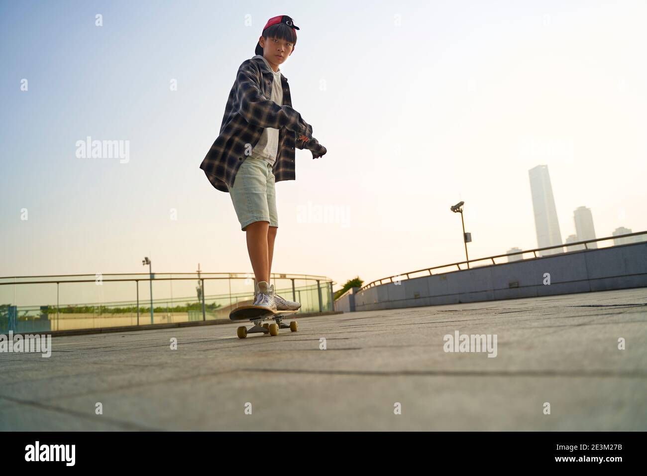 teenage asian child skateboarding outdoors on a pedestrian bridge Stock Photo