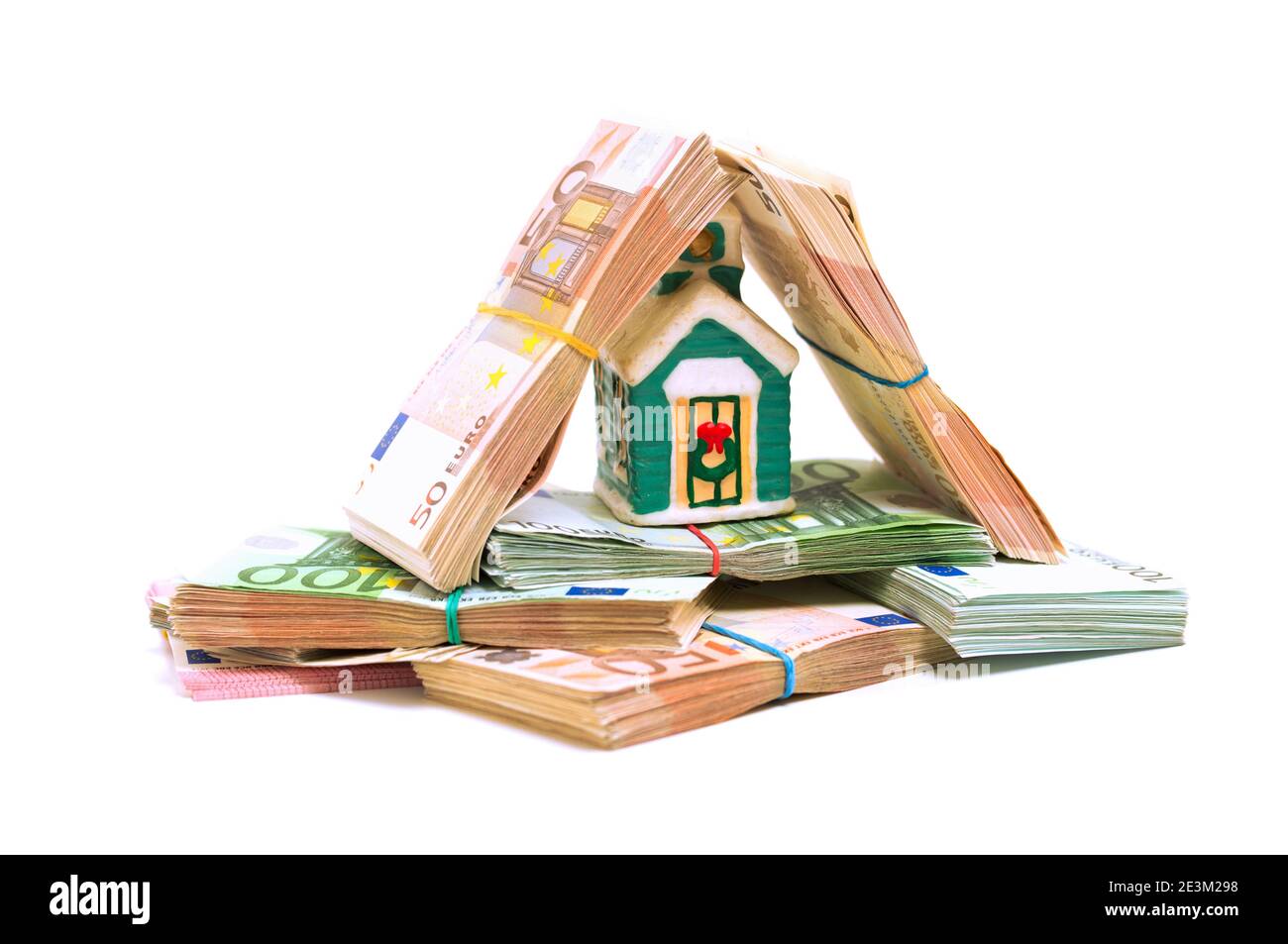 Stack pile of european money, Euro cash currency and a home covered with money isolated on white background. Savings for a new home, real estate prope Stock Photo