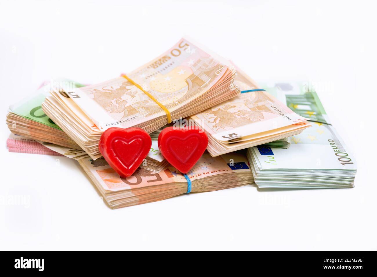 Stack pile of european money, Euro cash currency and two hearts on it isolated on white background. Savings for a a marriage, a new family conceptual Stock Photo