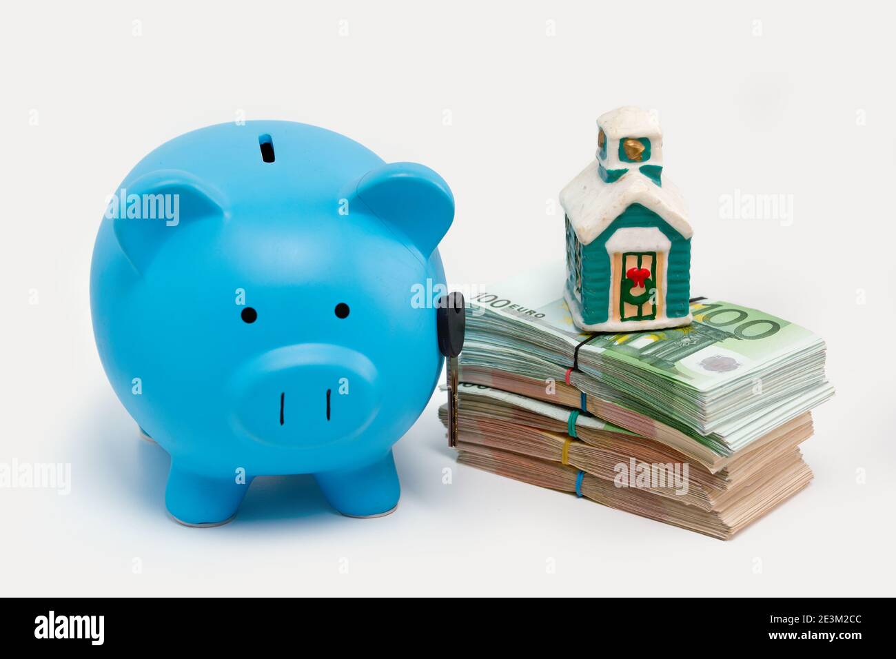 Stack pile of european money, Euro cash currency, a piggy bank with a key on it and a home on it isolated on white background. Savings for a new home, Stock Photo