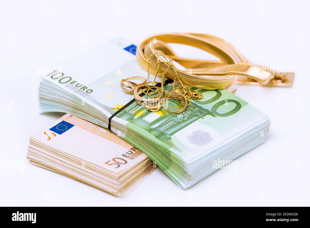 Gold and money. Stack pile of European union currency bills, euro banknotes and a bunch of golden jewelry isolated on white background. Savings bank a Stock Photo