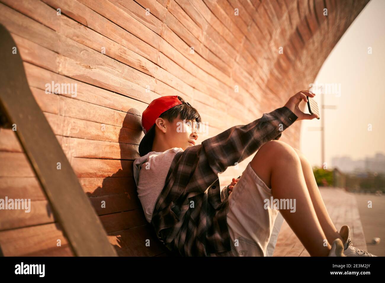 teenage asian skateboarder boy taking a selfie using cellphone Stock Photo