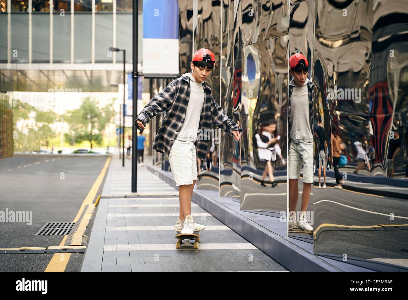 teenage asian child skateboarding outdoors in the street Stock Photo