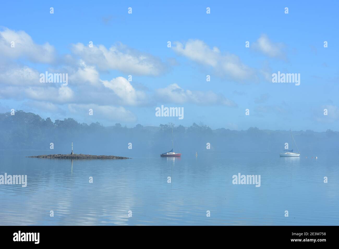 Hazy morning in calm harbour. Sky reflection on calm surface gives blue look to whole image. Stock Photo