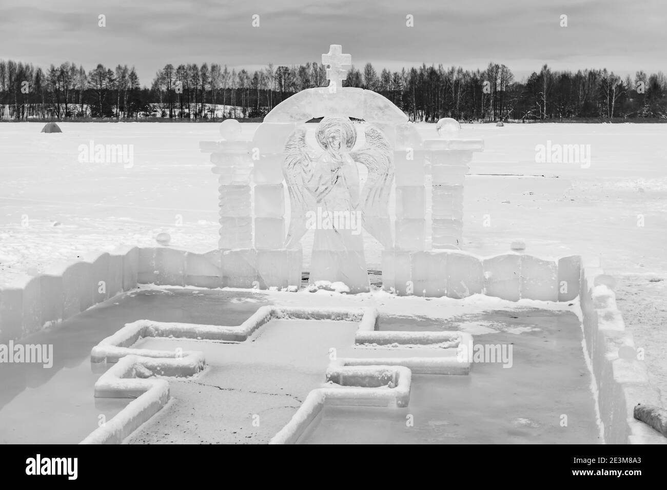 Font for dipping into an ice hole for the baptism of christ and ice sculpture in the form of an angel and a cross Stock Photo