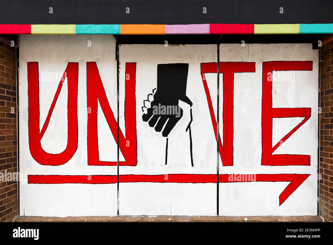 Painted mural on boards over a storefront window asking for unity during the civil unrest after the killing of George Floyd in Minneapolis, Minnesota Stock Photo