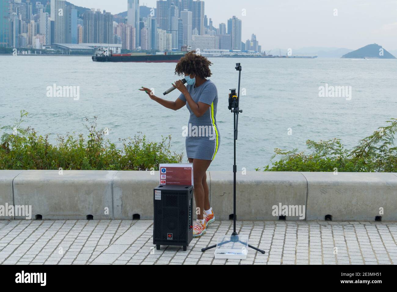 Hong Kong November 29 2020 : Woman Street Performer Wearing Mask and Singing in West Kowloon Culture District during Coronavirus (COVID-19) outbreak Stock Photo