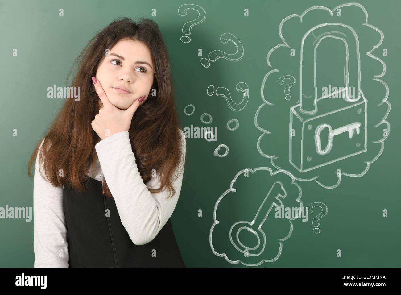 Pre-adolescent child shows on his cheek and thinking how to open the lock on green background Stock Photo