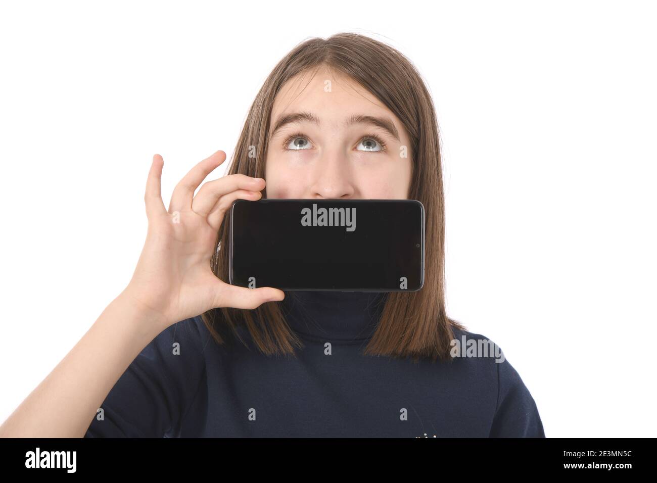 Pre-adolescent girl holding in front of his face black smartphone with blank screen. isolated on white background. High resolution photo. Full depth o Stock Photo
