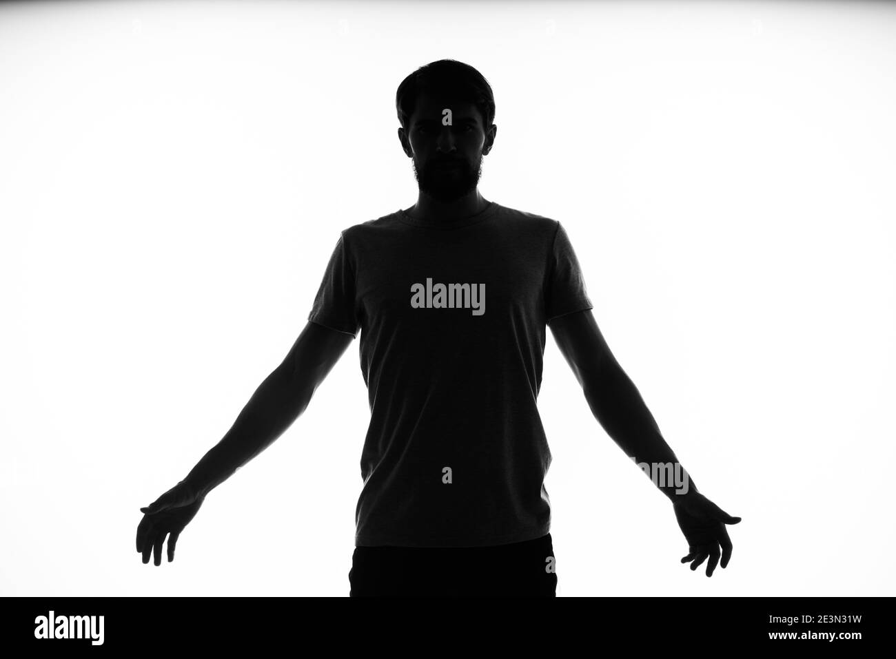 black silhouette of a man who gestures with his hands on a light ...