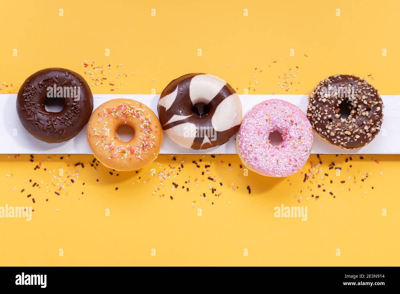 Flat lay composition with mixed donuts on yellow background. Stock Photo