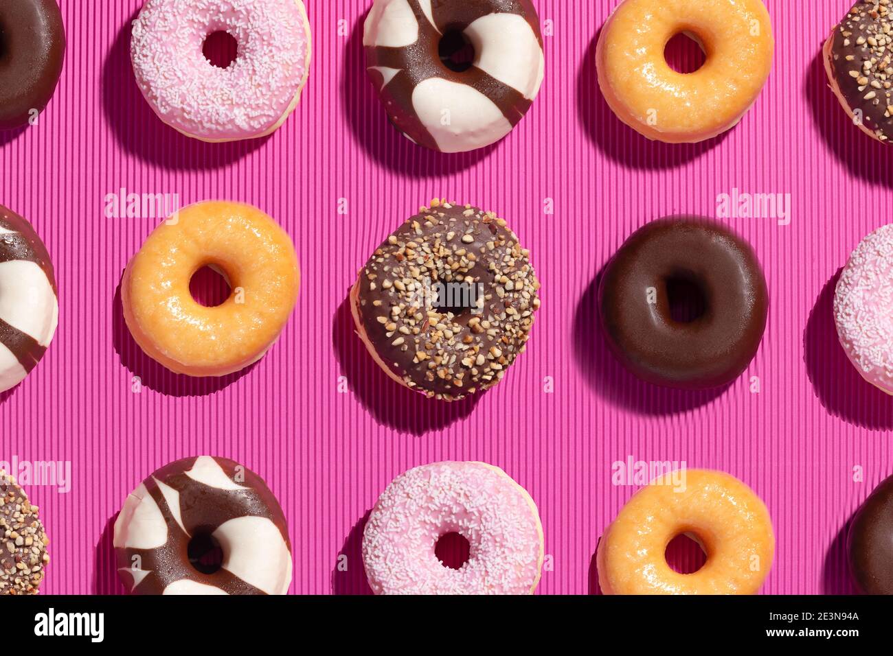 Flat lay composition of mixed donuts on pink background. Stock Photo