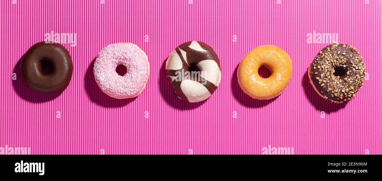Flat lay composition with mixed donuts on  pink background. Stock Photo