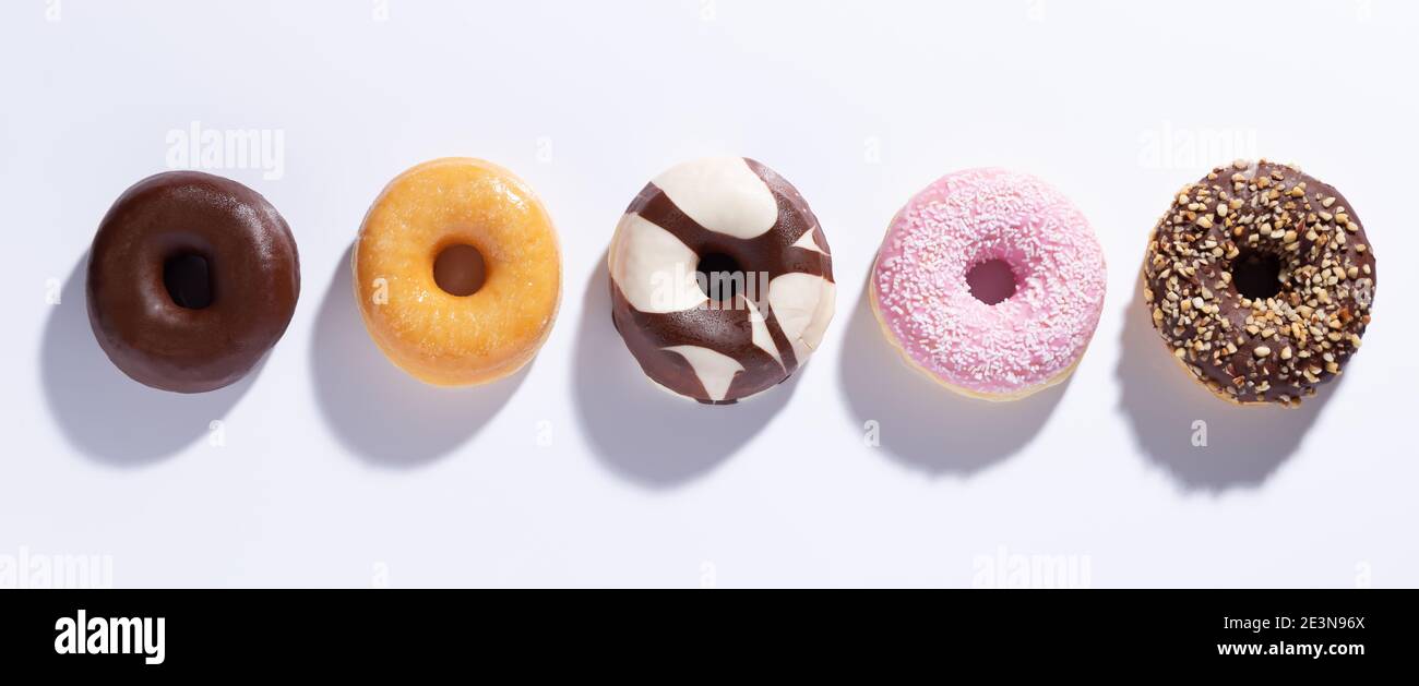 Flat lay composition with mixed donuts on white background. Stock Photo