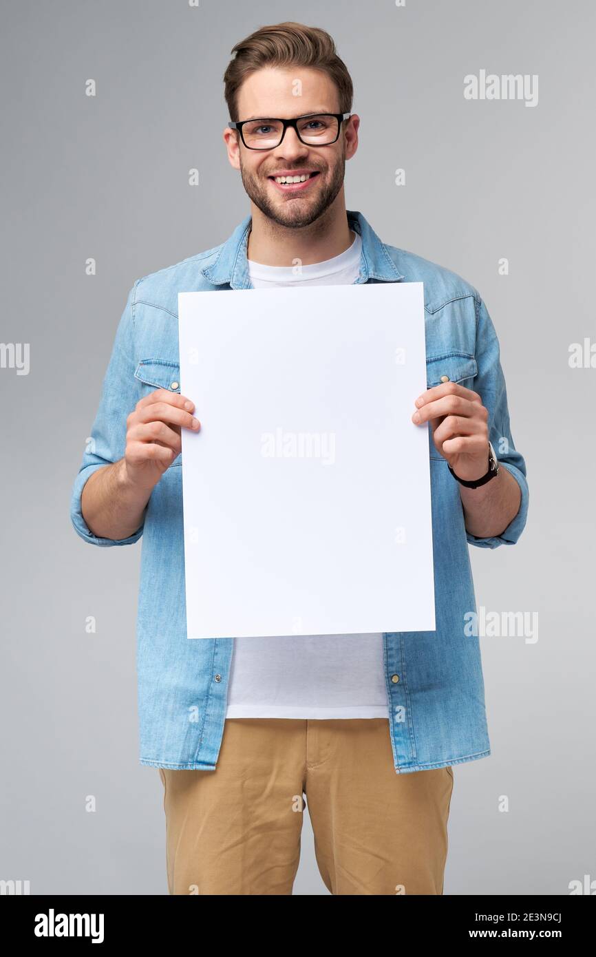 Portrait of a happy handsome young man holding blank white card or sign ...