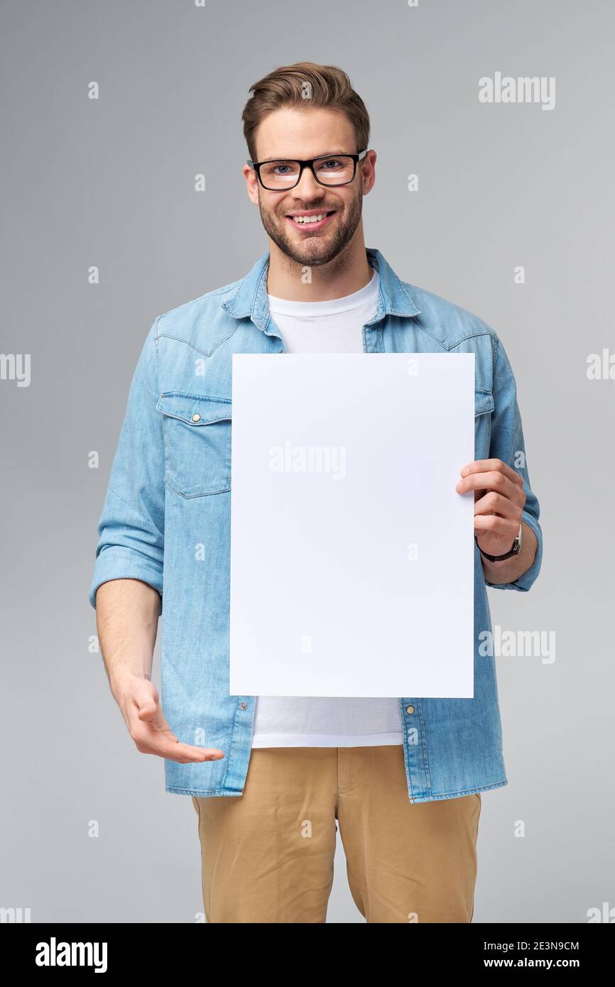Portrait of a happy handsome young man holding blank white card or sign ...