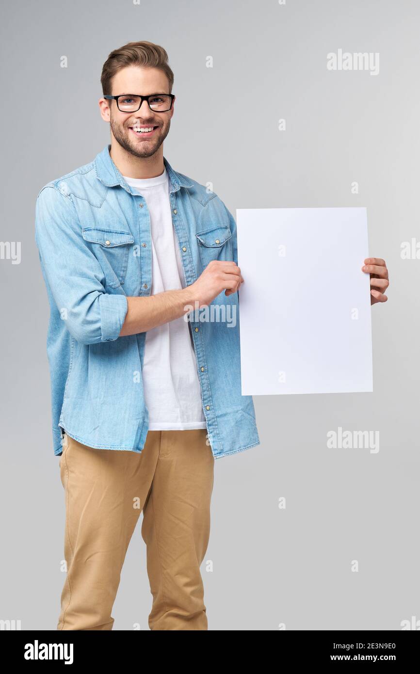 Portrait of a happy handsome young man holding blank white card or sign ...