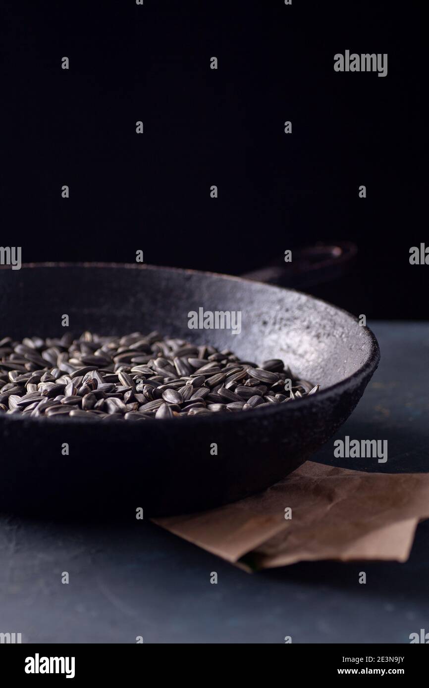 sunflower seeds in a black charred cast iron skillet with a handle and a paper craft bag on a