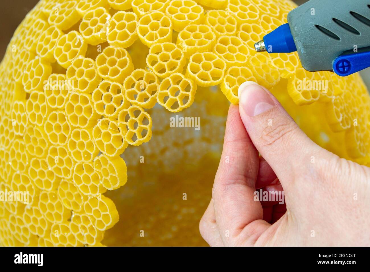 Woman glues pasta with a hot glue gun during the manufacture of crafts  Stock Photo - Alamy