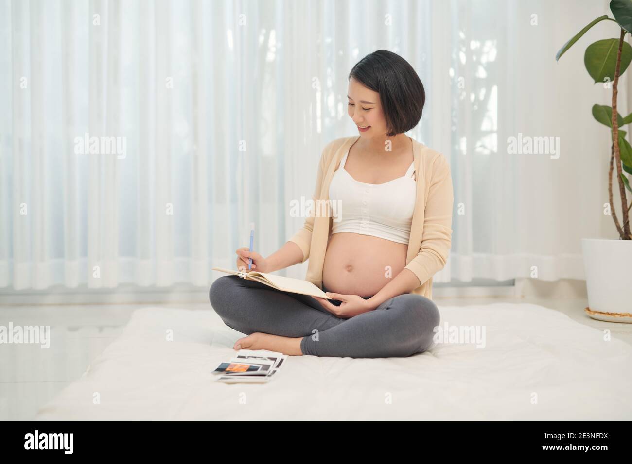regnant woman lie down looking at a sonogram ultrasonography picture of her unborn baby Stock Photo