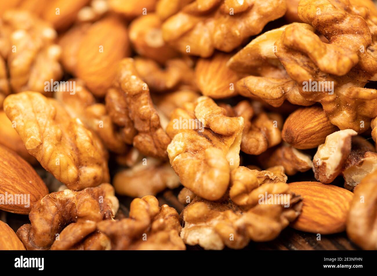 Almonds and walnuts scattered on the table. Close-up, selective focus Stock Photo