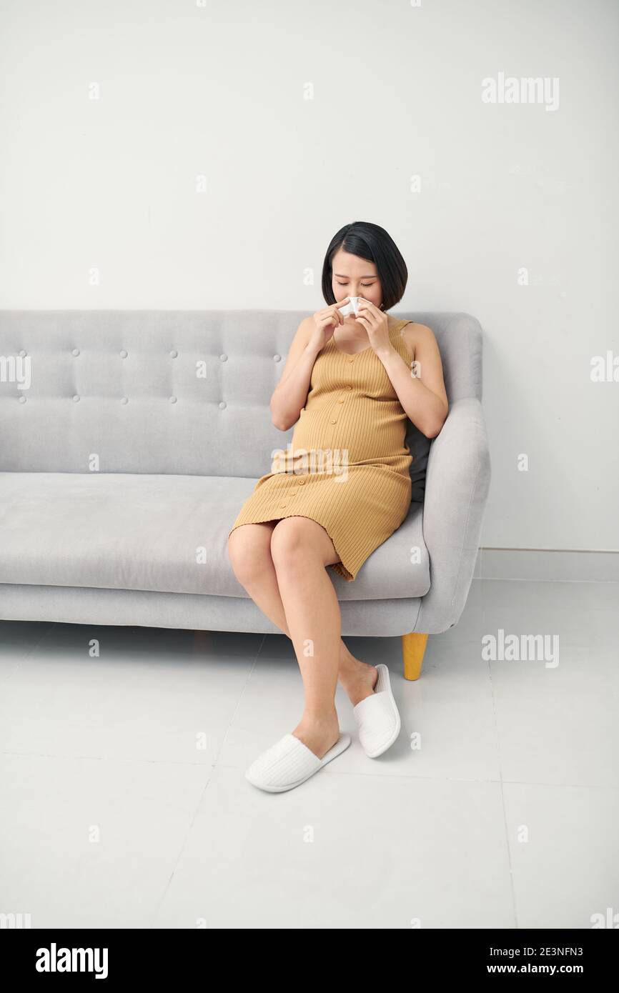 Asian pregnancy woman having a cough and cold fever sitting on sofa at