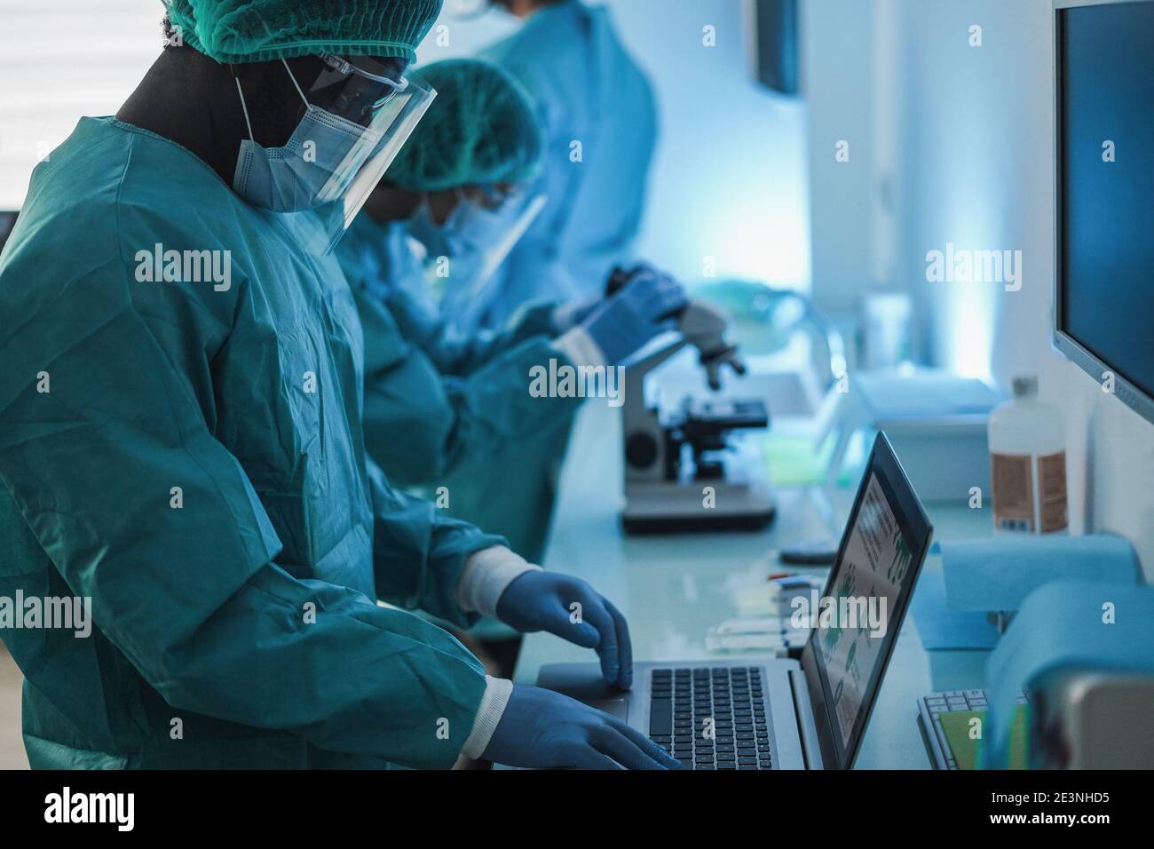 Medical workers in hazmat suit working with laptop computer and micoroscope inside laboratory hospital during coronavirus outbreak - Focus on african Stock Photo