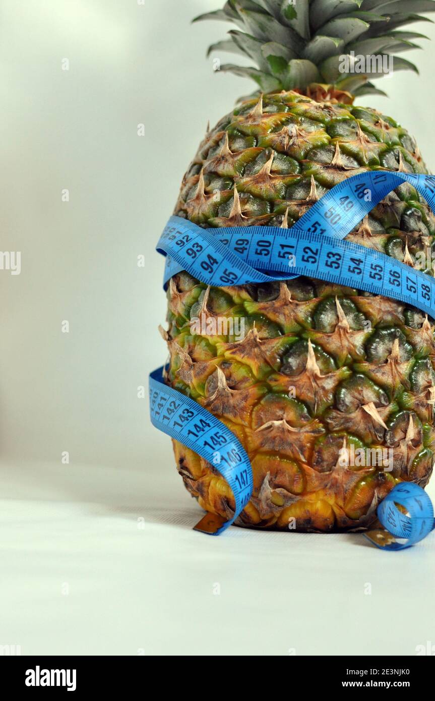 Pineapple wrapped with blue tailoring meter on white background, close up Stock Photo