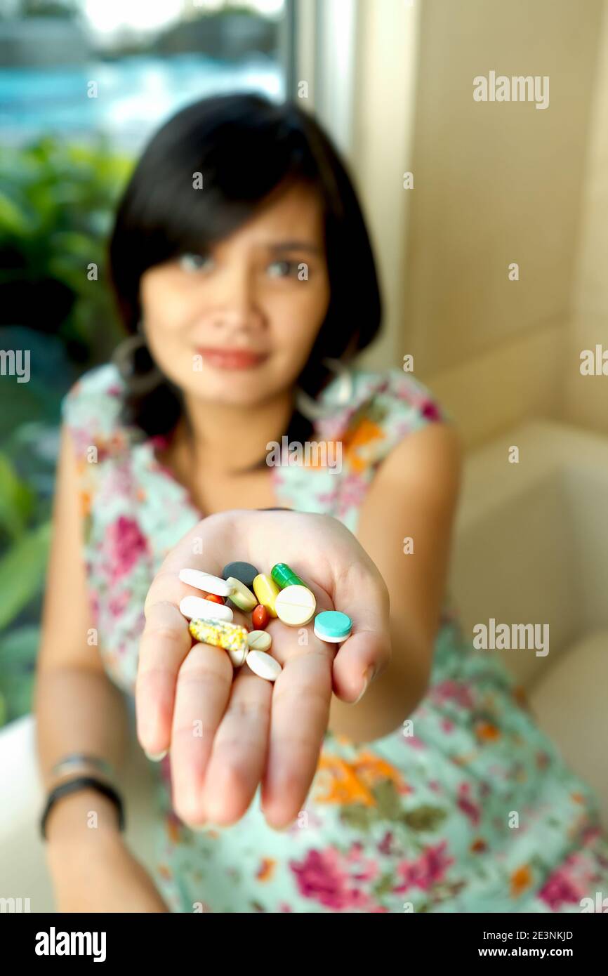 Pregnant Southeast Asian ethnic woman showing various prescribed supplements and vitamins Stock Photo