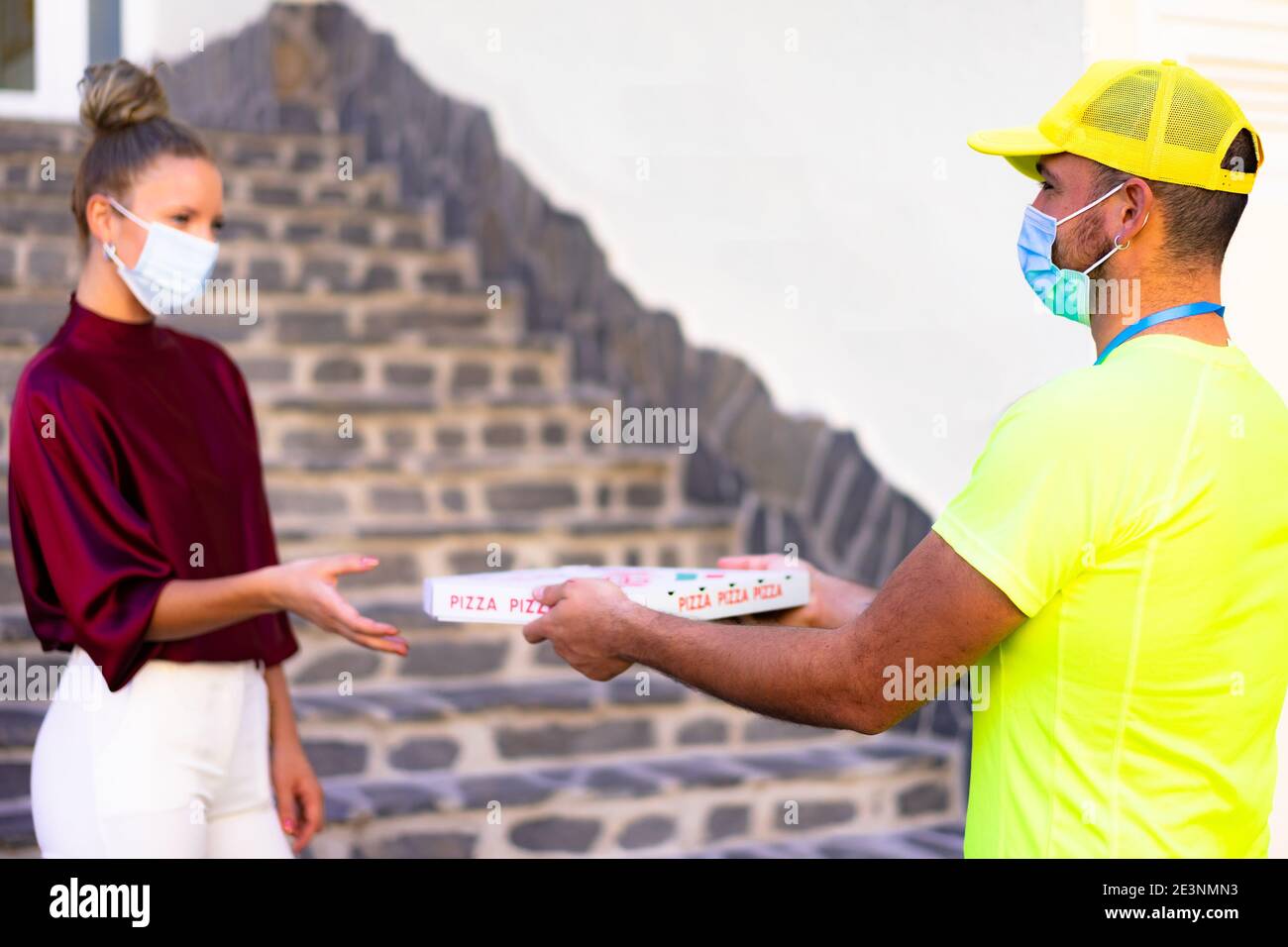 Delivery man employee in yellow cap and t-shirt uniform face mask hold food order pizza box. Service quarantine pandemic coronavirus virus flu 2019-nc Stock Photo