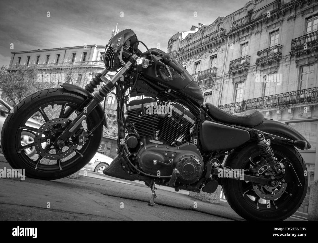 Harley Davidson motorcycle on a street in a french city with old historical buildings in the background - black and white Stock Photo
