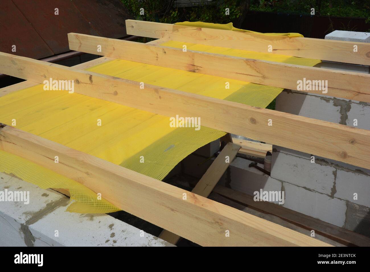 Building the roof frame with ceiling joists and rafters over the walls from autoclaved aerated concrete of a home addition construction using a vapor. Stock Photo