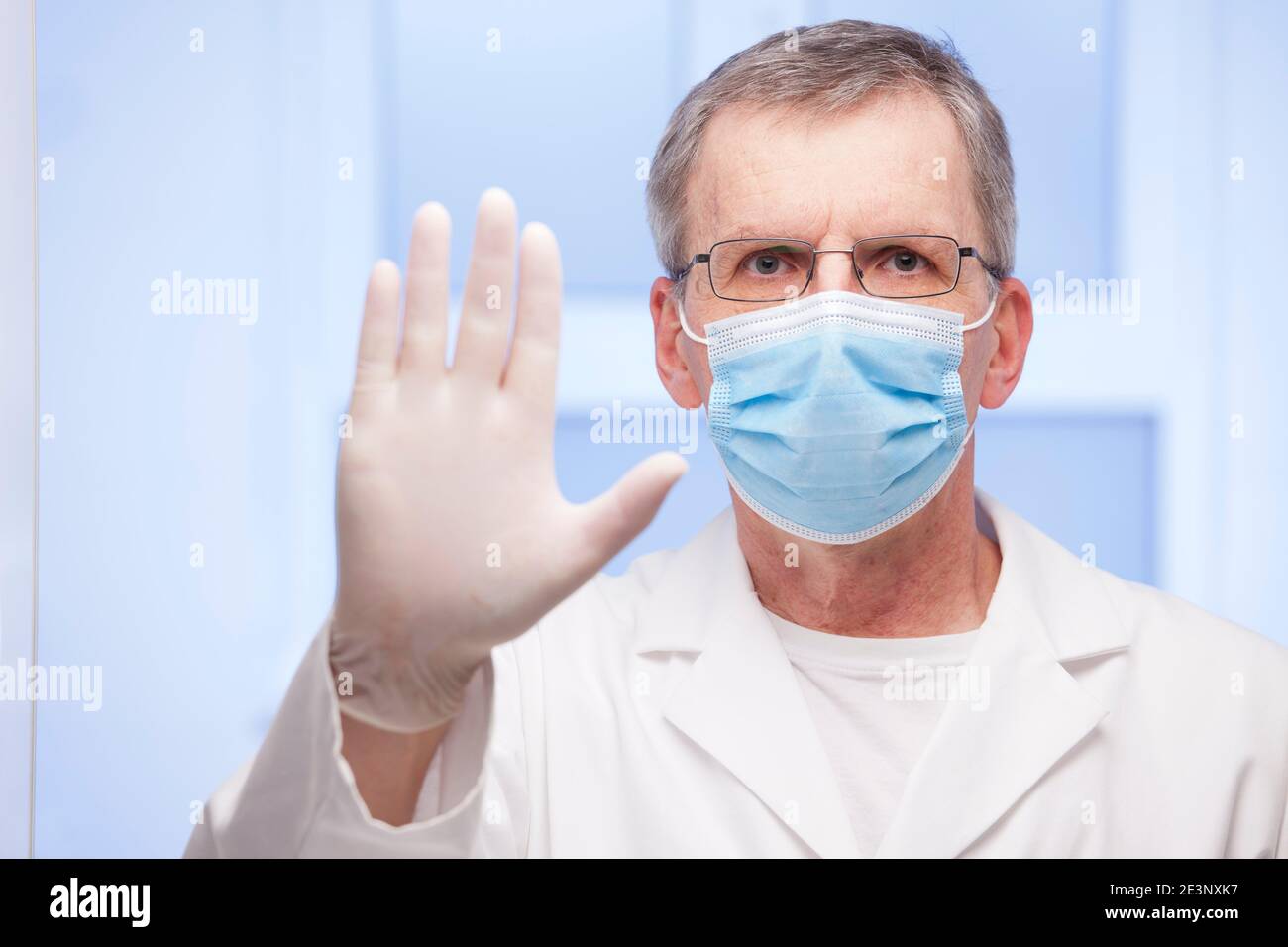 Doctor with surgical mask gesturing stop for covid-19 - focus on the face Stock Photo