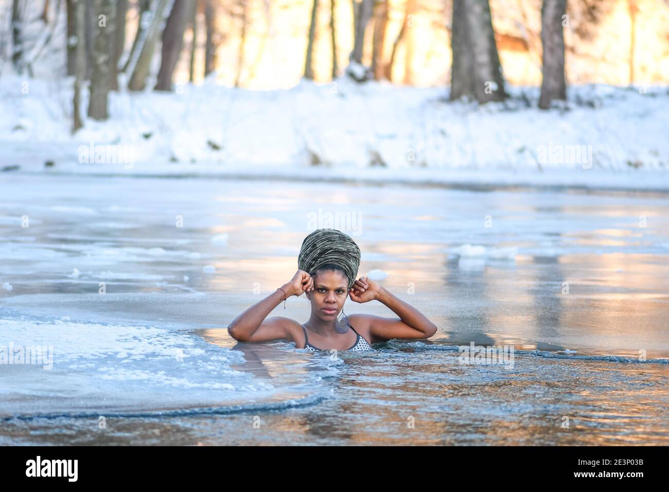 Beautiful girl enjoying winter and swimming in the cold water of a lake