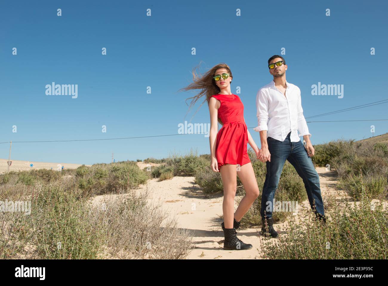 young couple walking through a desert landscape under the blue sky Stock Photo