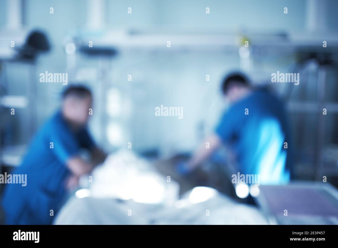 Two male medical workers working with critical condition patient in the intensive care unit, unfocused background. Stock Photo
