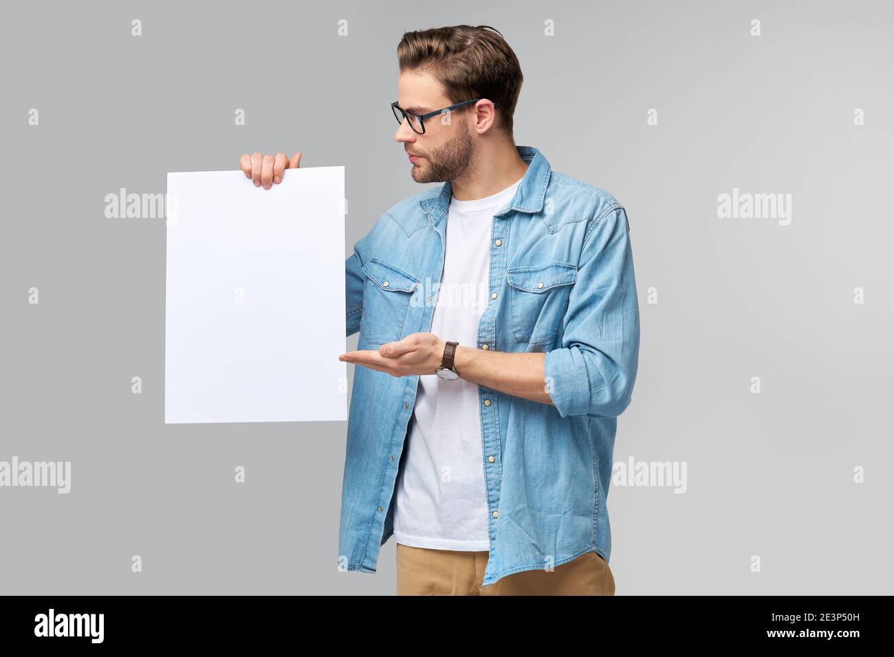 Portrait of a happy handsome young man holding blank white card or sign ...