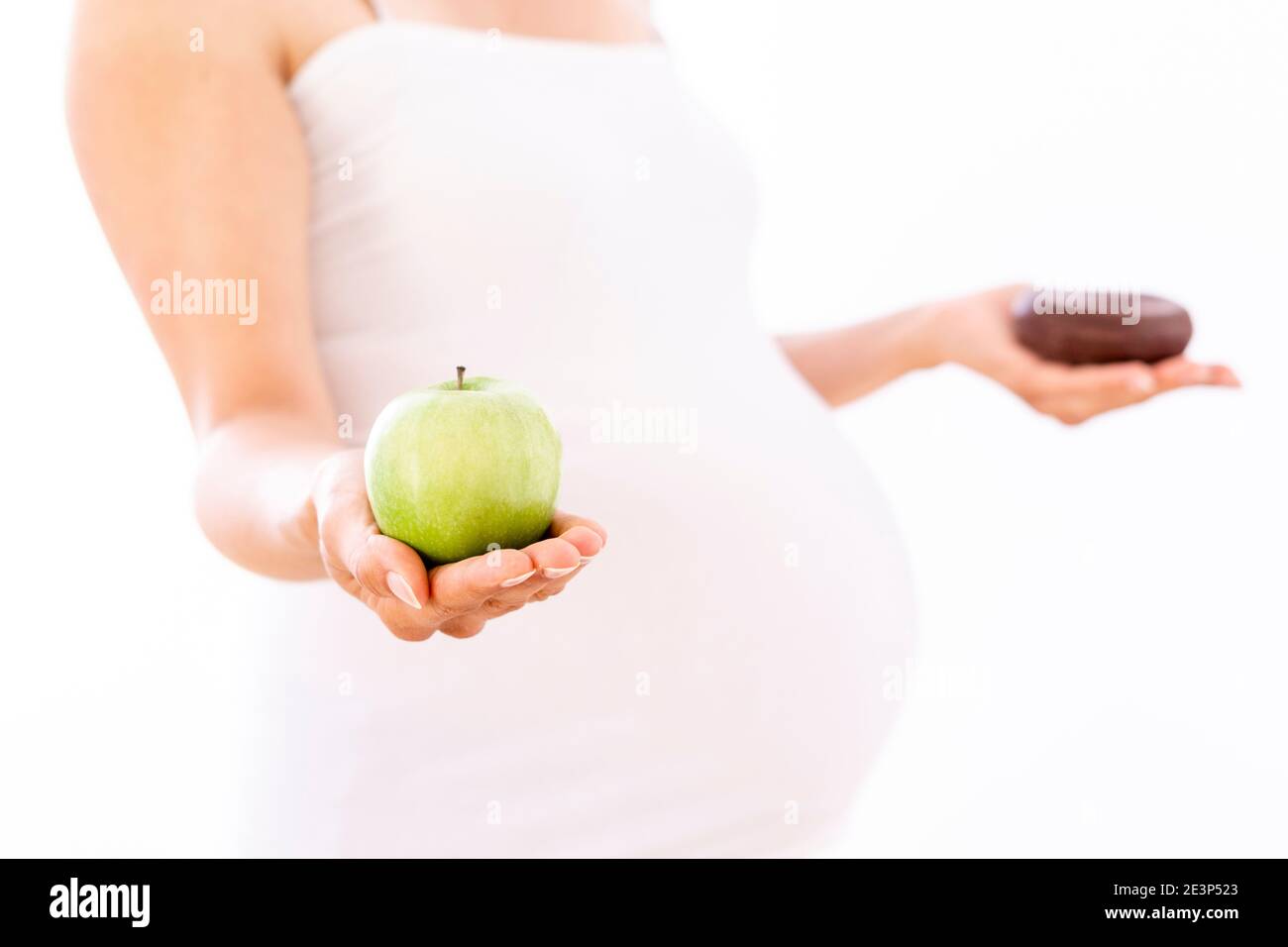 Pregnant woman choosing healthy apple over unhealthy donut on white background Stock Photo